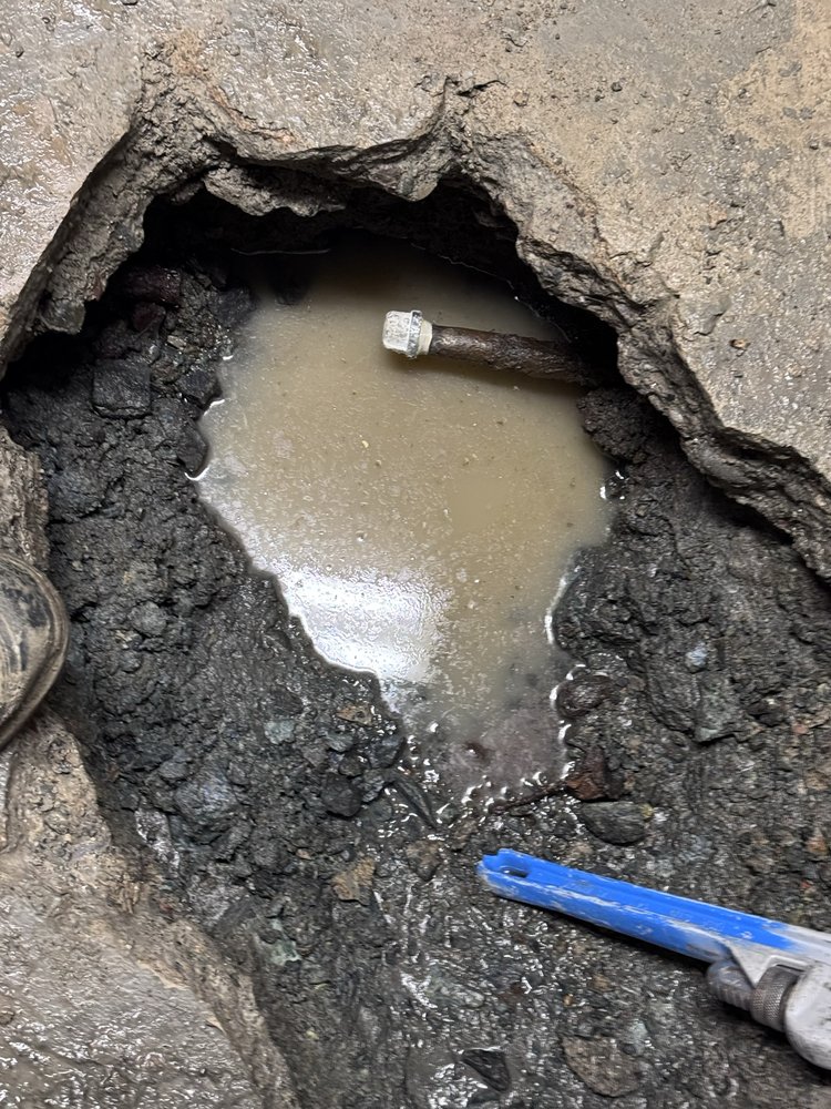Close-up of a corroded plumbing pipe with an active leak found and exposed during a repair job