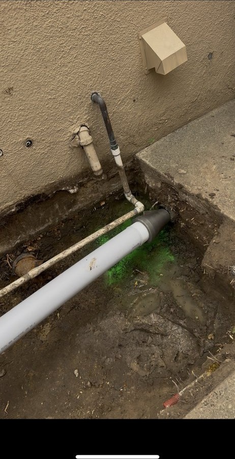 Sewer cleanout access point with green dye test water confirming proper drainage flow